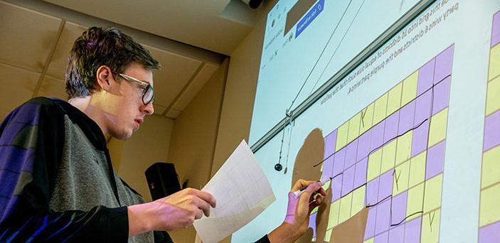 在数学和政治课上，一名BSU学生站在白板前将网格划分为区域
