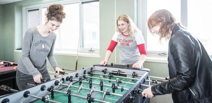 学生们在游戏室一起玩桌上足球